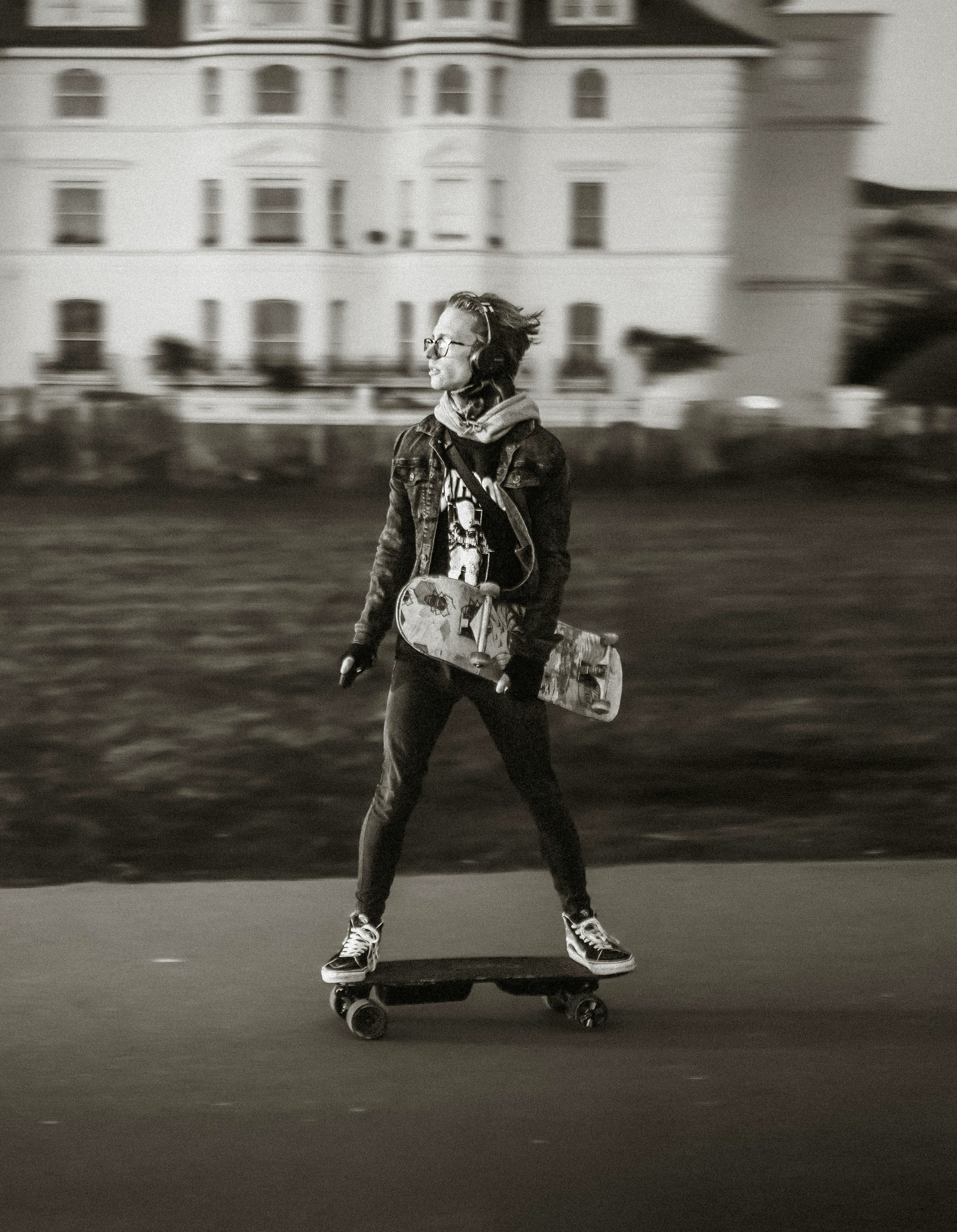 grayscale photo of woman in black jacket and pants walking on road